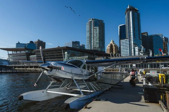 Un hidroavión atado a un muelle del centro con el centro de convenciones y las torres de cristal detrás