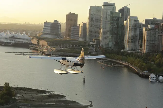 A floatplane gliding in to land on Coal Harbour with downtown towers behind